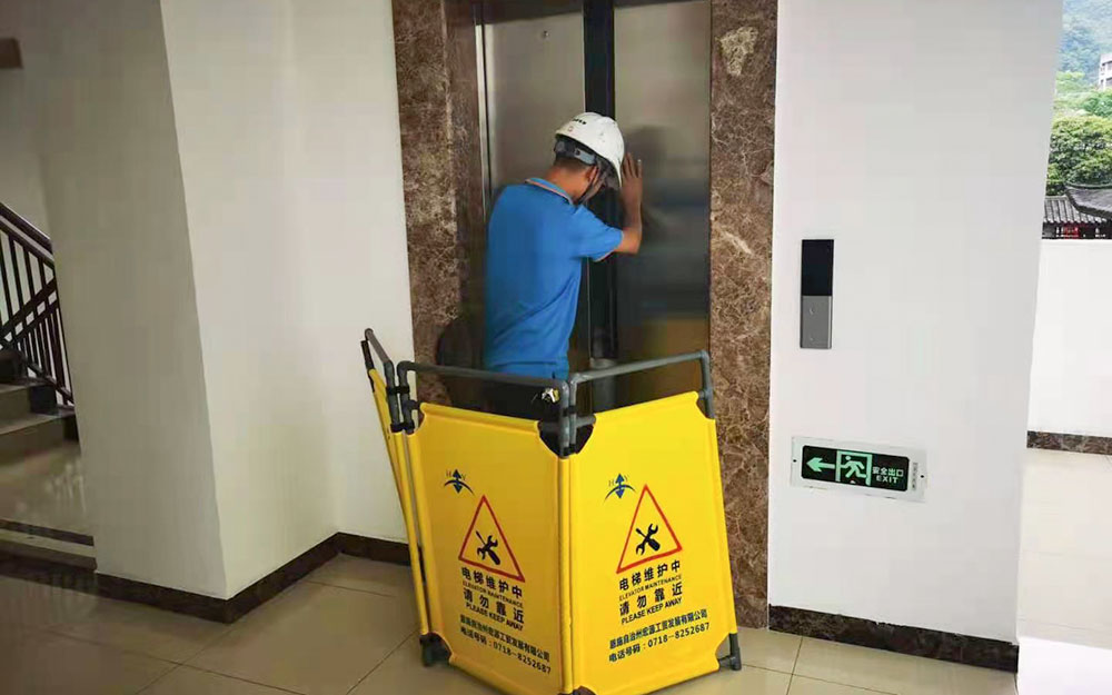 到达故障电梯所在处，在基站放置警示护栏，用三角钥匙打开层门观察轿厢所处位置